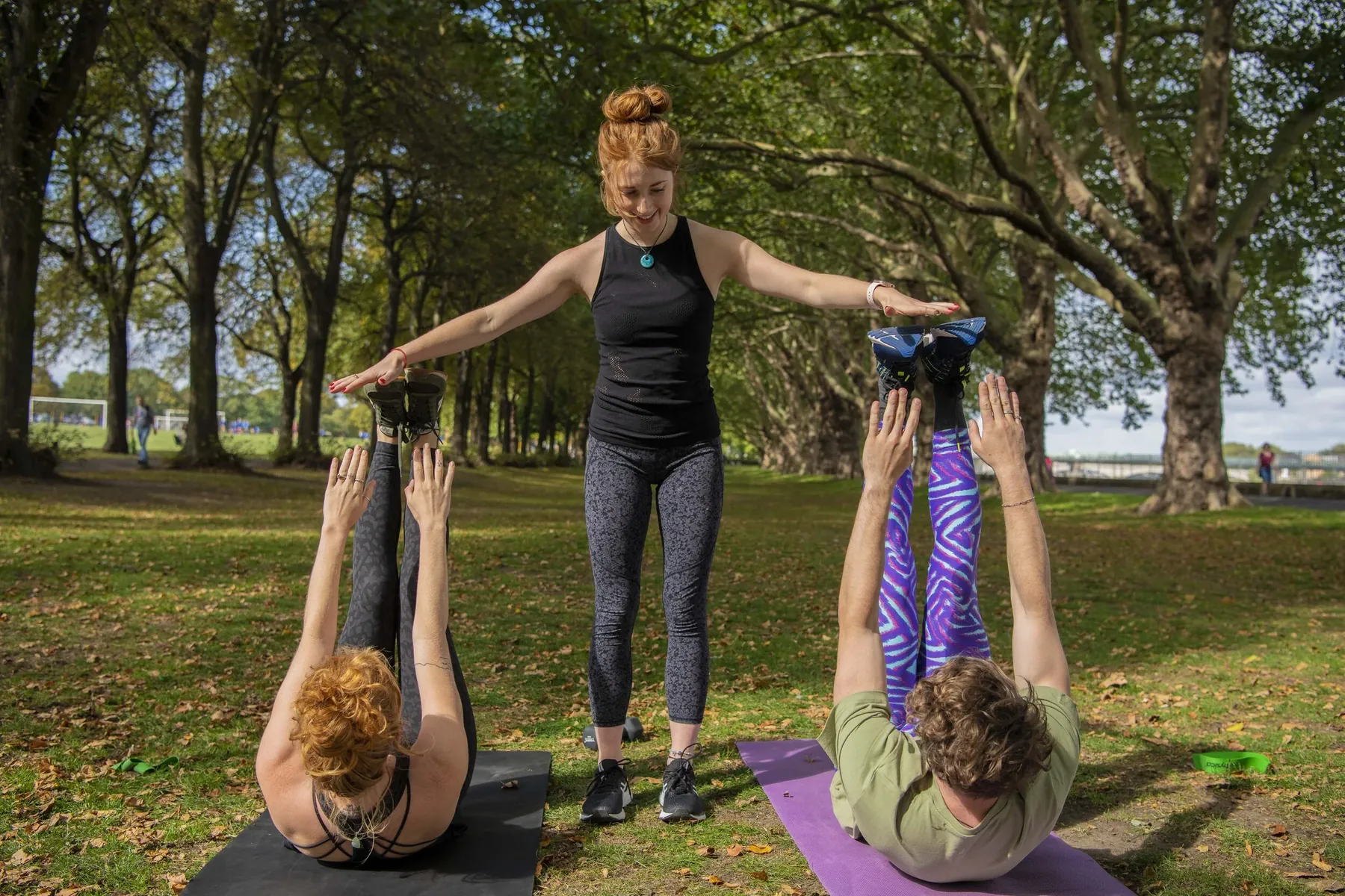 Bridget coaching two clients through a core exercise in the park